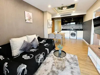 Modern living room with stylish decor and open kitchen featuring washing machine and sleek appliances.