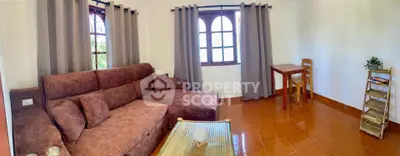 Cozy living room with brown sofa, elegant curtains, and natural light through arched windows.