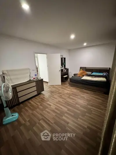 Spacious bedroom with wooden flooring and modern furnishings