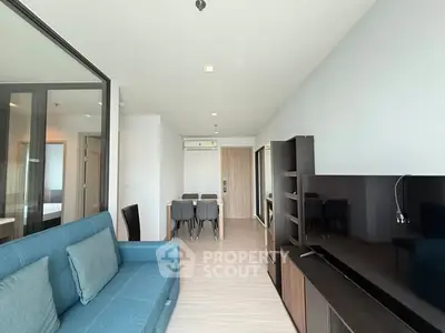 Modern living room with blue sofa and dining area in open layout apartment.