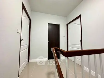 Modern hallway with three doors and a staircase, showcasing sleek design and neutral tones.