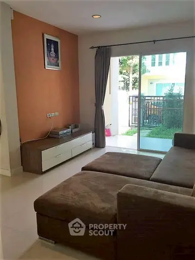 Cozy living room with sectional sofa and garden view through sliding glass doors.