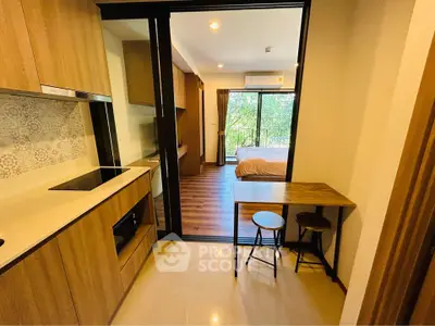 Modern studio apartment with open kitchen and cozy bedroom, featuring wooden flooring and large windows.