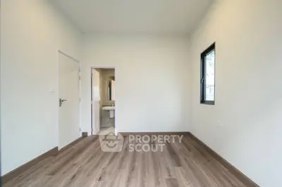 Spacious empty room with wooden flooring and bathroom access
