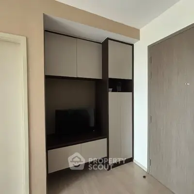 Modern apartment interior with sleek built-in storage and TV unit, showcasing minimalist design.
