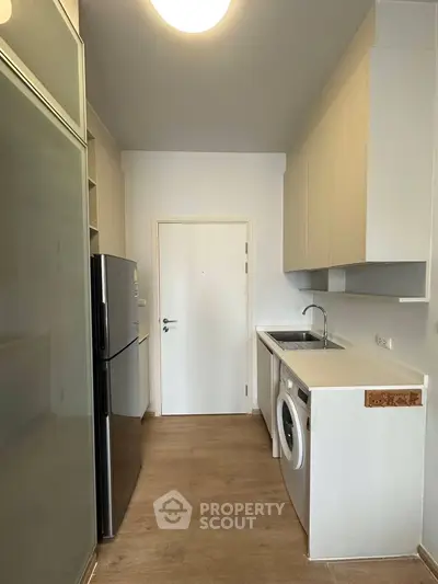 Modern kitchen with sleek appliances and washing machine in compact layout