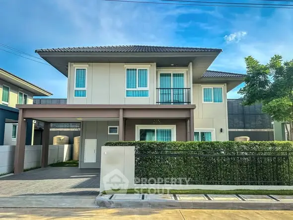 Modern two-story house with sleek design and lush greenery in a serene neighborhood.