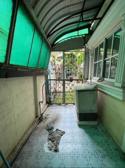 Covered outdoor laundry area with sink and garden view
