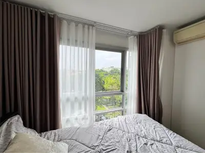 Cozy bedroom with large windows offering a scenic view, featuring elegant curtains and a comfortable bed.
