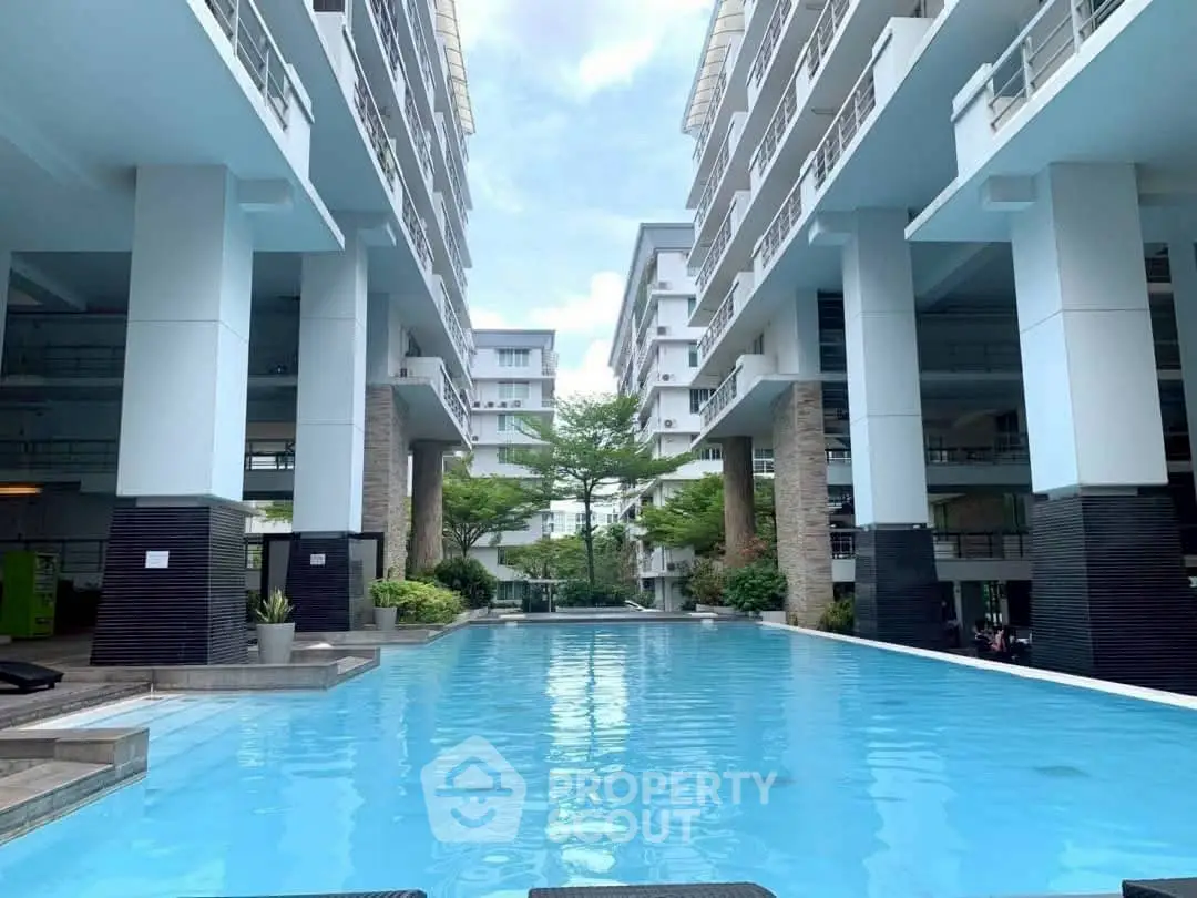 Luxurious modern apartment complex with stunning pool and lush greenery.