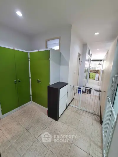 Spacious hallway with green storage cabinets and modern tile flooring
