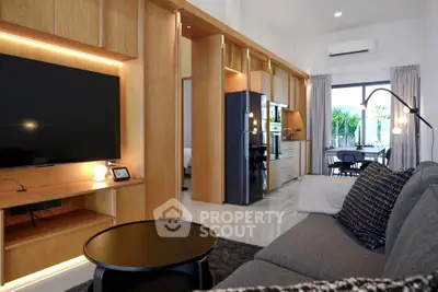 Modern living room with sleek design and open kitchen layout, featuring stylish furniture and large TV.