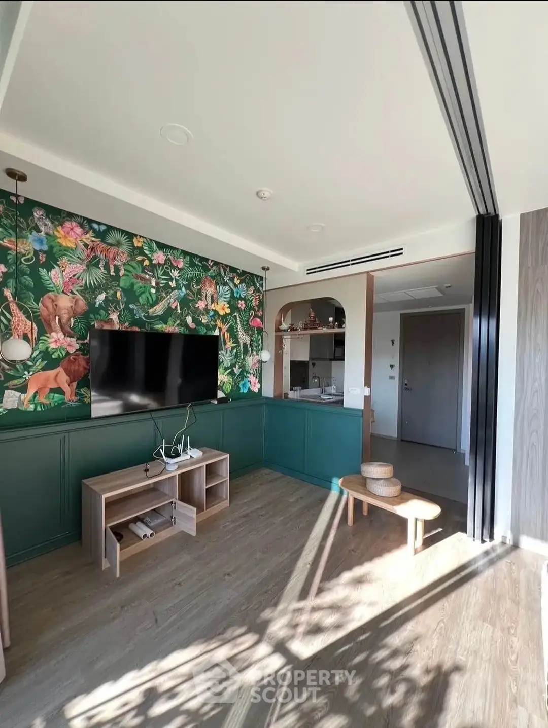 Stylish living room with vibrant jungle-themed wallpaper and modern TV setup, perfect for cozy relaxation.
