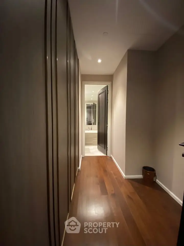 Elegant hallway leading to a modern bathroom with sleek design and wooden flooring.