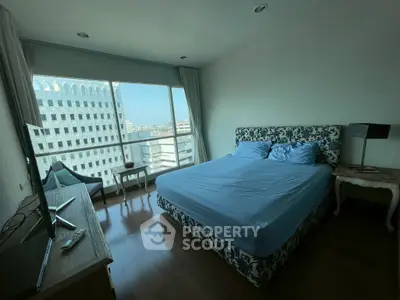 Spacious bedroom with large window offering stunning city views, elegant decor, and modern furnishings.