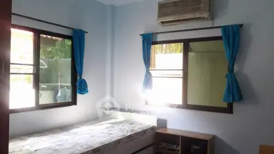 Cozy bedroom with natural light, featuring air conditioning and simple furnishings for a comfortable living space.
