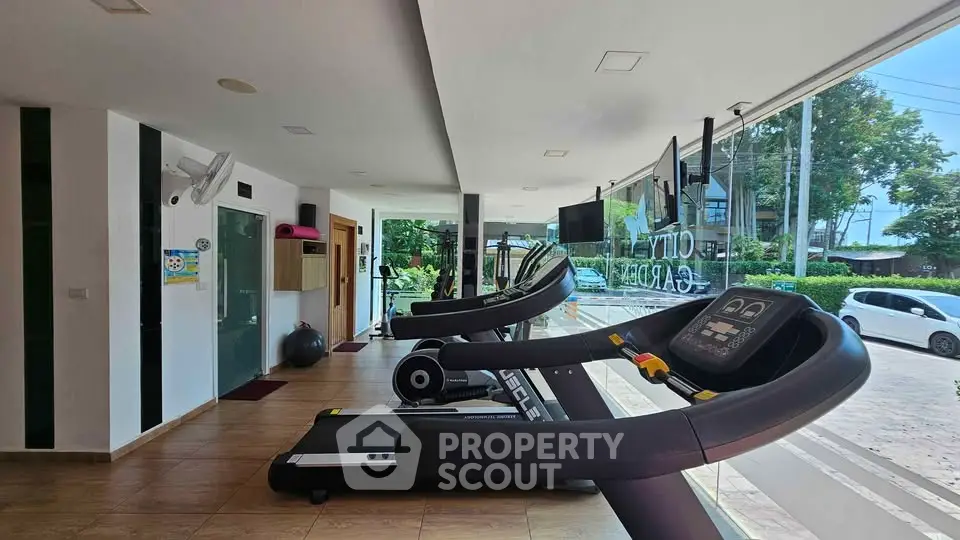 Modern gym with treadmills and large windows in a residential complex.