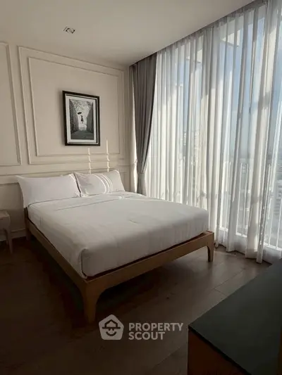 Elegant bedroom with large windows and modern decor, offering a serene city view.