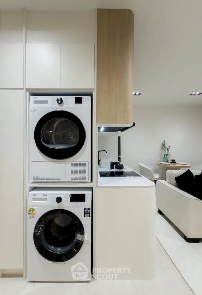 Modern apartment interior with stacked washer and dryer next to sleek kitchen area.