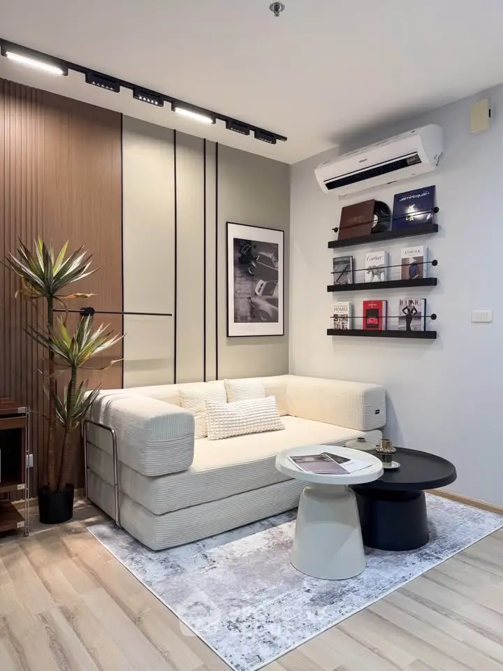 Modern living room with stylish decor, featuring a cozy sofa, wall-mounted shelves, and air conditioning.