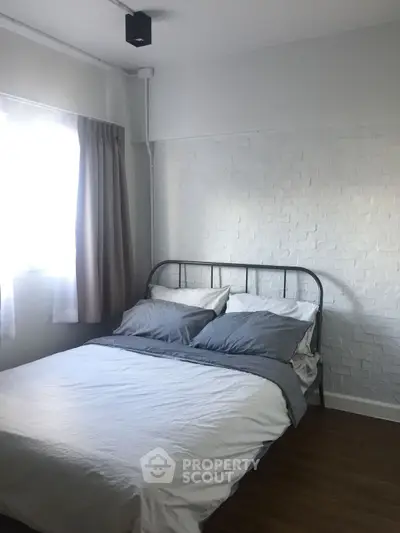 Cozy bedroom with modern metal bed frame and white brick accent wall, perfect for restful nights.