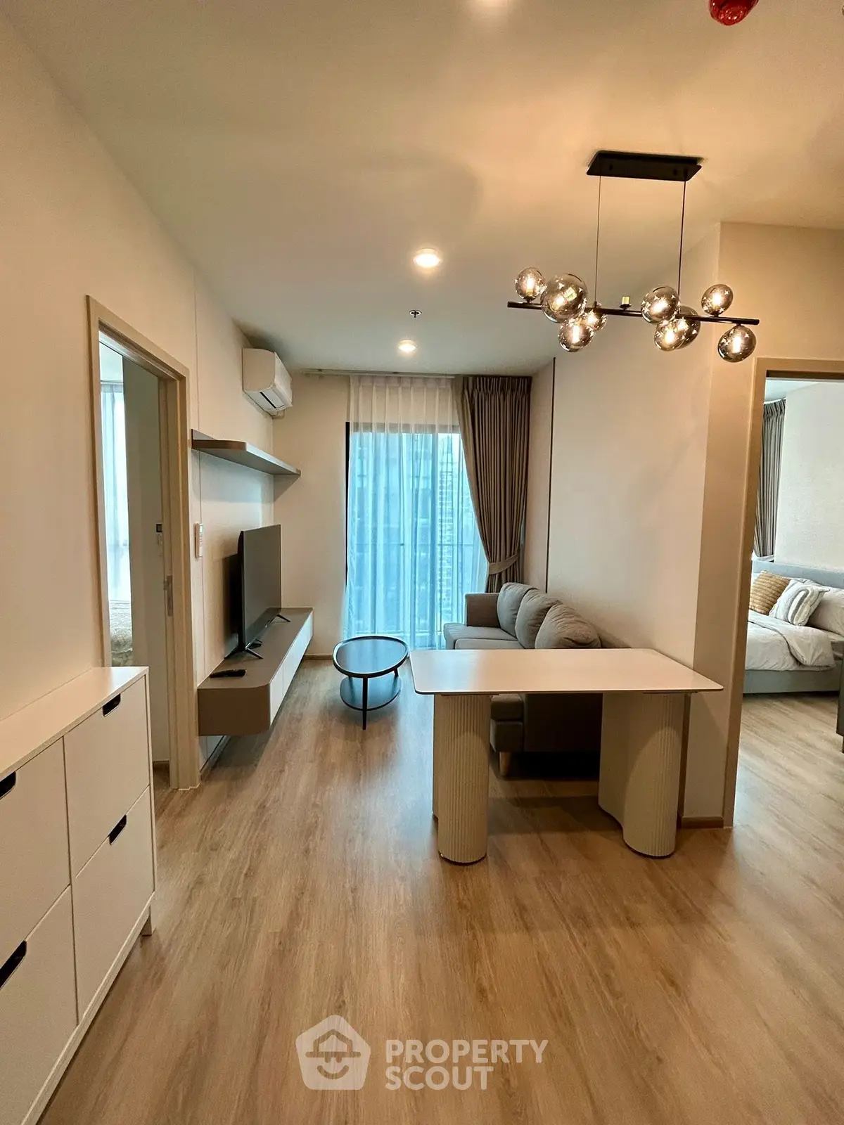 Modern living room with stylish decor and natural light, featuring a cozy seating area and sleek TV setup.