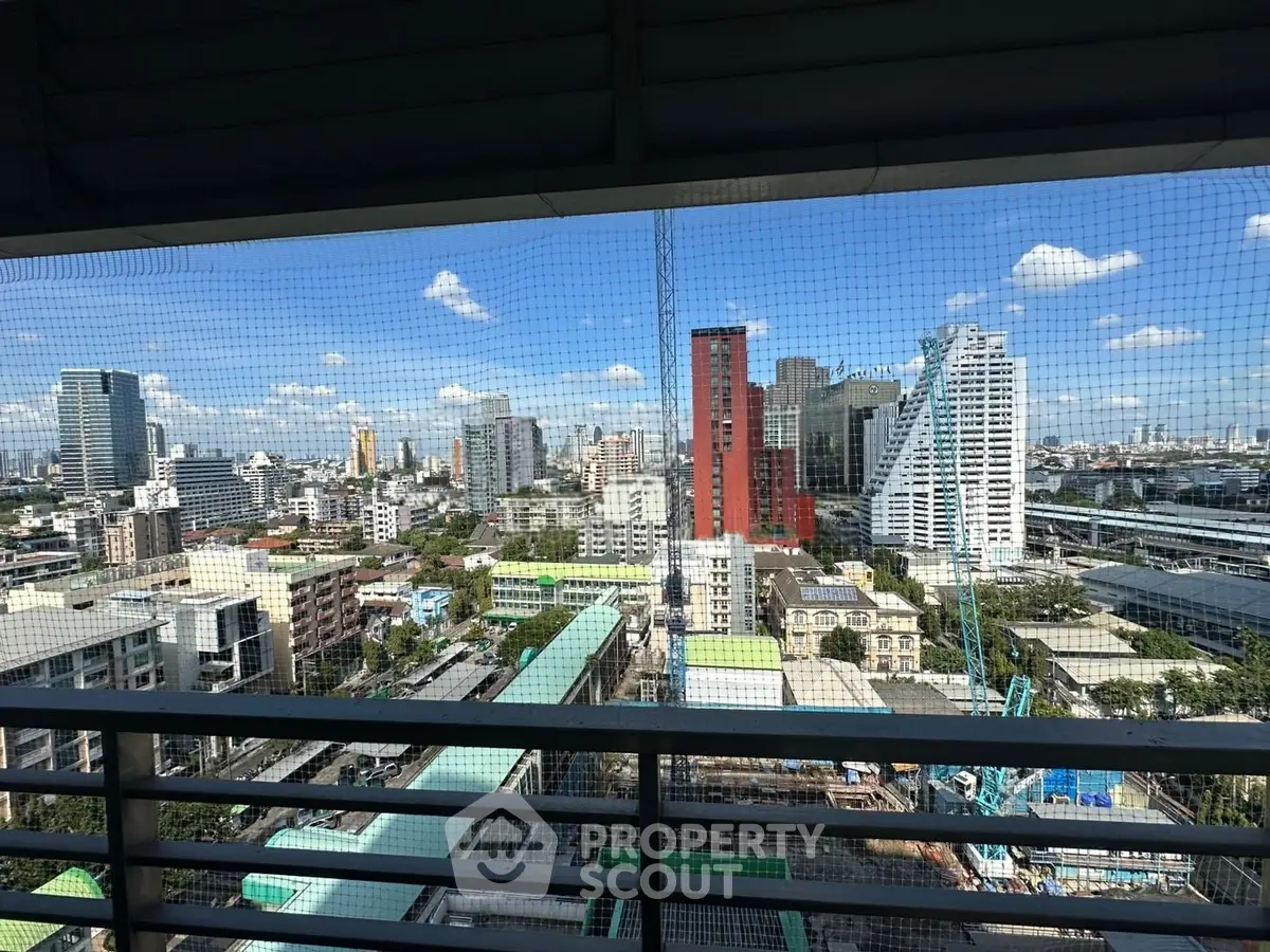Stunning cityscape view from a high-rise balcony showcasing urban skyline and clear blue skies.