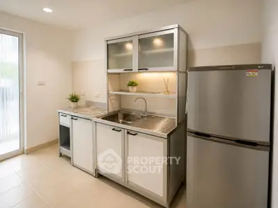 Modern kitchen with sleek cabinets and stainless steel fridge in a bright apartment.