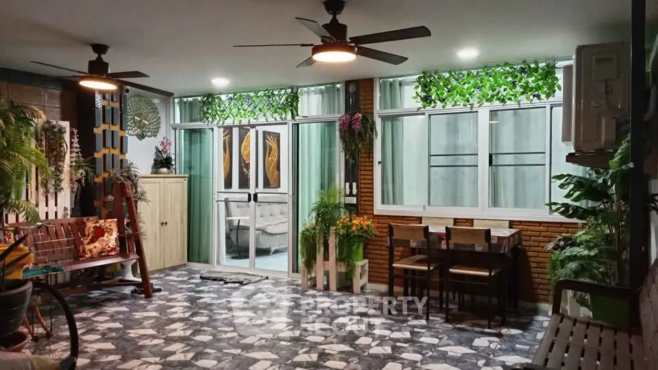 Charming living room with modern decor, ceiling fans, and lush greenery accents.