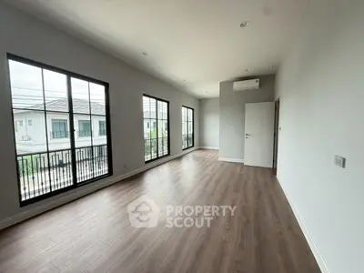 Spacious empty room with large windows and wood flooring in modern home