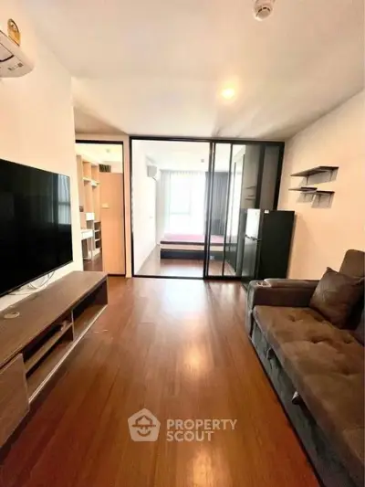 Modern living room with wooden flooring and glass partition leading to bedroom