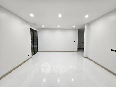 Spacious modern living room with sleek white tiles and recessed lighting.