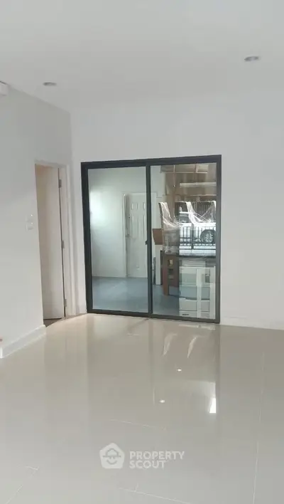 Spacious modern interior with glossy tiled floors and large glass doors, perfect for contemporary living.