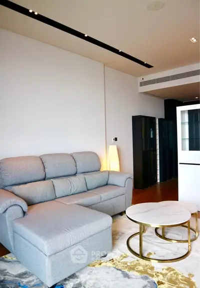 Modern living room with stylish gray sofa and chic round coffee table