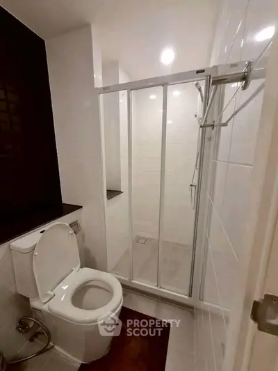 Modern bathroom with glass shower enclosure and sleek white tiles.