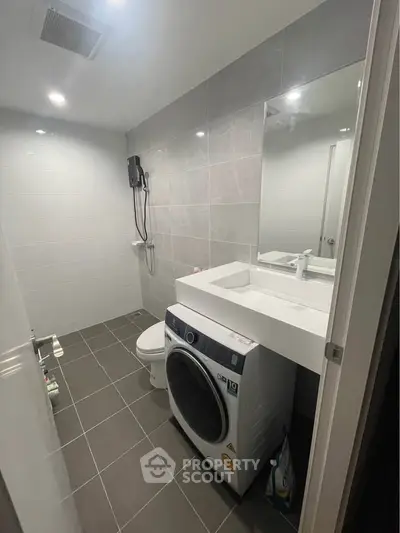 Modern bathroom with washing machine and sleek fixtures in a contemporary apartment.