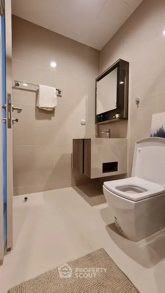 Modern bathroom with sleek fixtures and neutral tones, featuring a wall-mounted vanity and contemporary toilet.