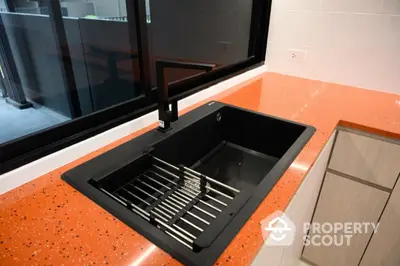 Modern kitchen with sleek black sink and vibrant orange countertop