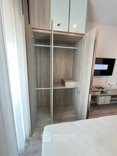Modern bedroom with open wardrobe and sleek TV setup