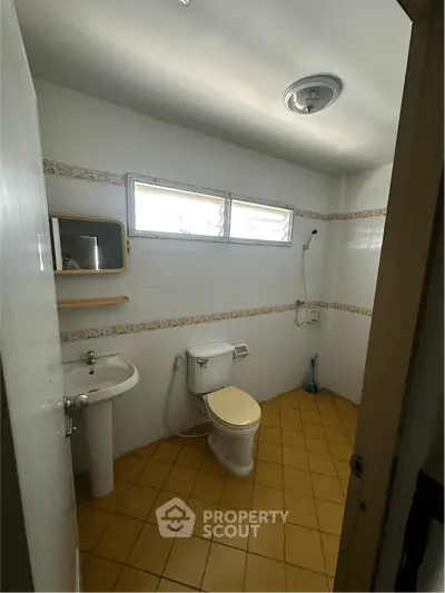 Spacious bathroom with natural light, featuring a toilet, sink, and shower area, ideal for modern living.