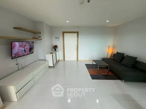 Modern living room with sleek furniture and wall-mounted TV in a bright apartment.