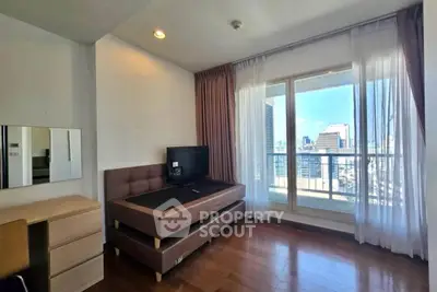 Bright bedroom with city view and balcony access, featuring modern furniture and wooden flooring.