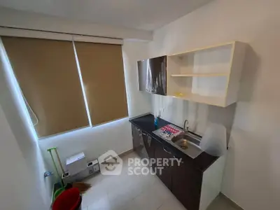 Compact kitchen with modern cabinets and sink, featuring a closed layout and natural light from window.
