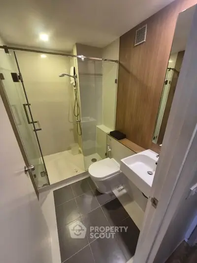Modern bathroom with glass shower and sleek fixtures in contemporary apartment.