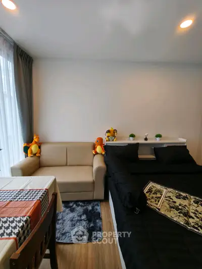 Cozy living room with sofa and bed, featuring plush toys and modern decor.