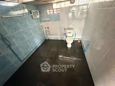 Spacious bathroom with modern blue tile design and essential fixtures.