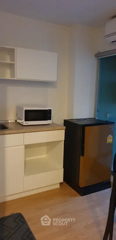 Modern kitchen with microwave and compact fridge in cozy apartment