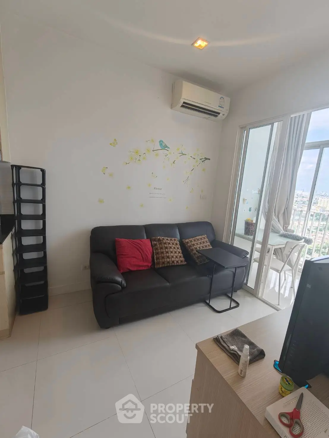 Modern living room with balcony view, featuring sleek furniture and air conditioning.