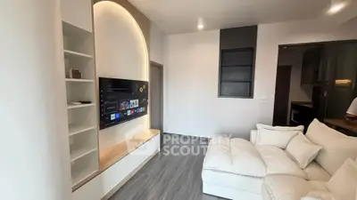 Modern living room with sleek TV setup and cozy white sofa in a stylish apartment.
