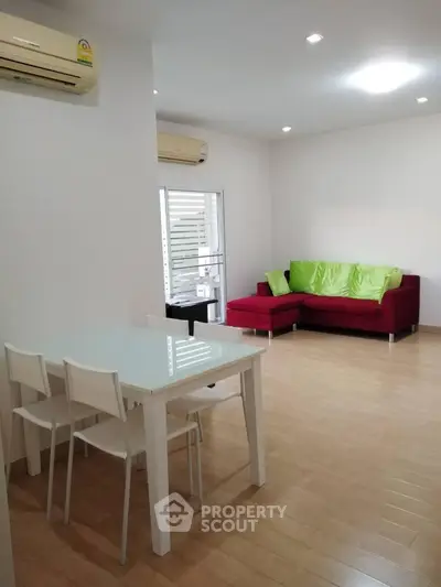 Modern living room with red sofa and dining area, featuring sleek design and bright ambiance.